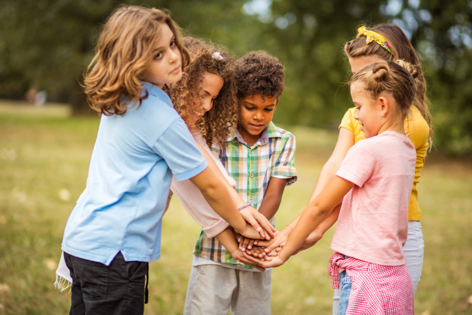 Children gathered in a circle, hands together in teamwork.