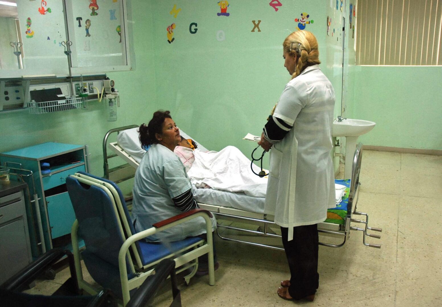 Nurse speaking with patient in green hospital room