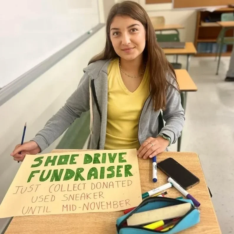 Student making shoe drive fundraiser poster in classroom